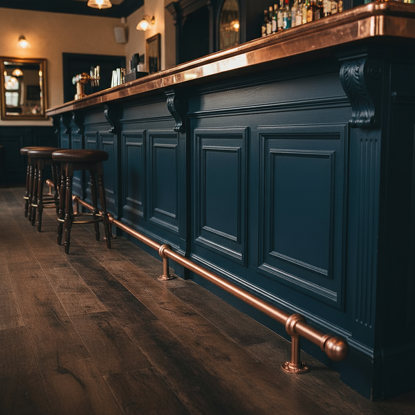 Copper finish bar foot rail with round steel tube, floor mounted brackets and ball end cap against a dark blue bar