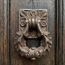 Load image into Gallery viewer, Ornate floral cast metal door knocker with an aged bronze finish on a wooden door
