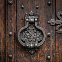 Load image into Gallery viewer, Gothic Tudor cast metal door knocker with a dark iron finish on a studded wooden door
