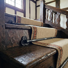 Load image into Gallery viewer, Tudor Trefoil Stair Rods with Hammered Bar, across a carpet runner on wooden stairs
